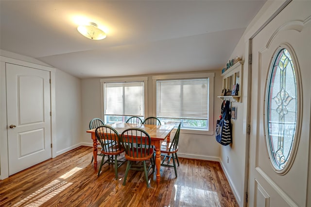 dining room with lofted ceiling, wood-type flooring, and a healthy amount of sunlight