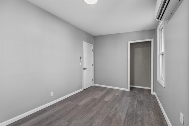 unfurnished bedroom featuring dark wood-type flooring, a closet, and a wall unit AC