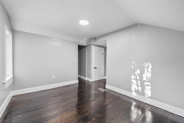 unfurnished room with lofted ceiling and dark wood-type flooring