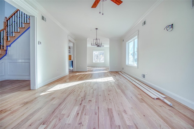 interior space featuring ceiling fan with notable chandelier, ornamental molding, and light hardwood / wood-style floors