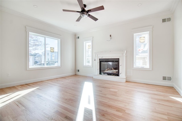 unfurnished living room featuring crown molding, ceiling fan, a high end fireplace, and light hardwood / wood-style floors