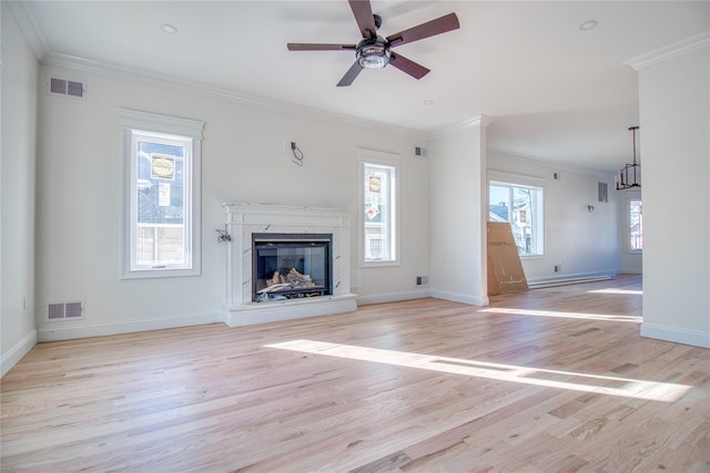 unfurnished living room with crown molding, a premium fireplace, and a wealth of natural light