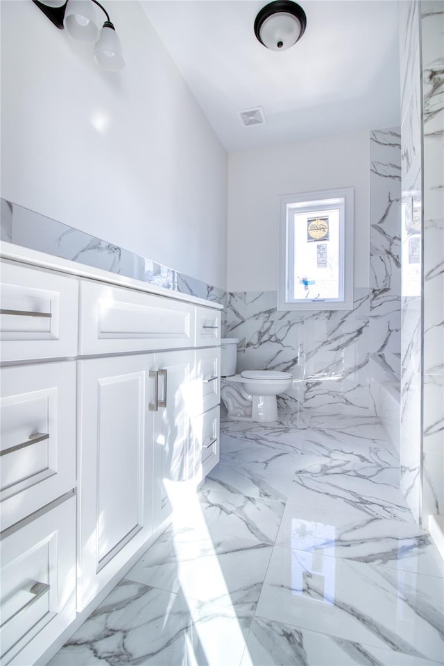 bathroom featuring tile walls, vanity, and toilet