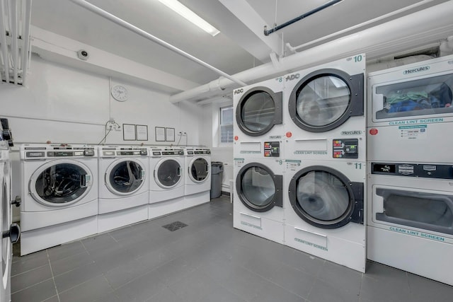 laundry area with stacked washer and dryer, washer and clothes dryer, and dark tile patterned flooring