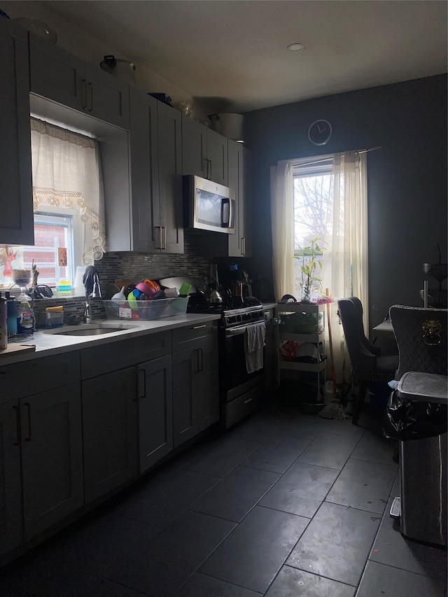 kitchen with gray cabinets, appliances with stainless steel finishes, sink, and backsplash