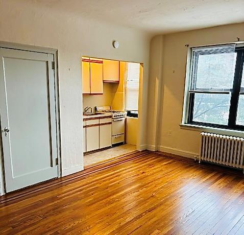 kitchen with gas range, sink, radiator, and light hardwood / wood-style floors