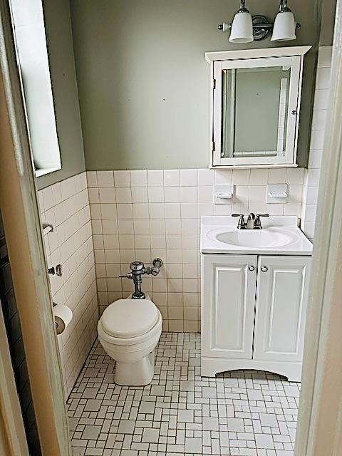 bathroom with tile patterned floors, toilet, tile walls, and vanity