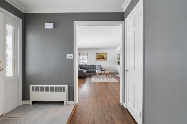 entrance foyer with radiator, wood-type flooring, and ornamental molding