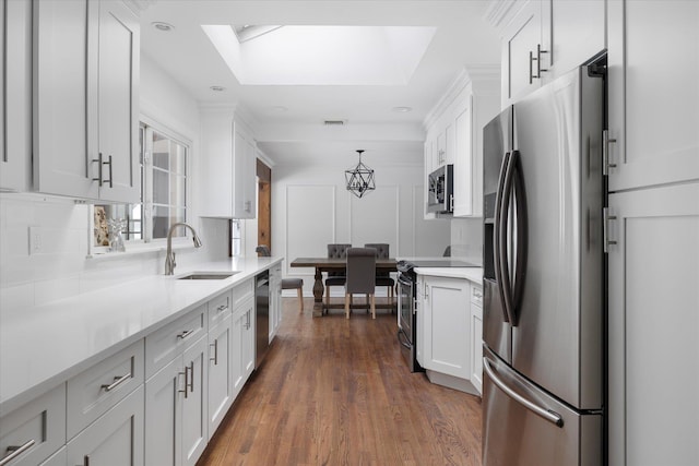 kitchen featuring pendant lighting, sink, white cabinetry, backsplash, and stainless steel appliances