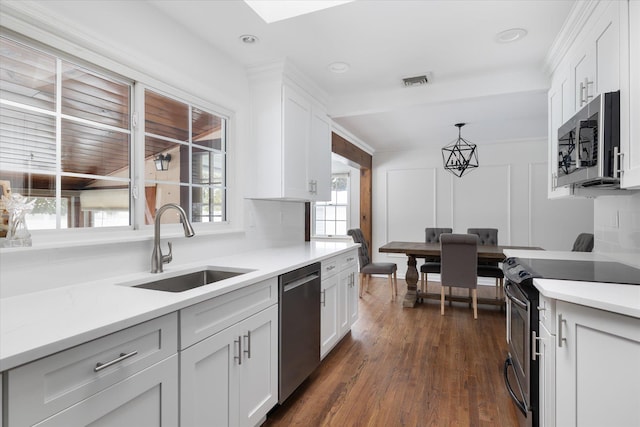 kitchen with hanging light fixtures, appliances with stainless steel finishes, sink, and white cabinets