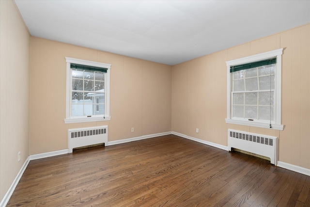 empty room featuring radiator and dark hardwood / wood-style flooring