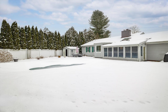 snowy yard with a sunroom and a storage unit