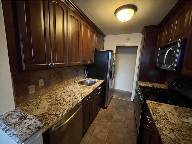 kitchen featuring sink, backsplash, stainless steel appliances, dark brown cabinetry, and light stone countertops