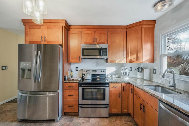 kitchen featuring sink, appliances with stainless steel finishes, backsplash, hanging light fixtures, and light stone countertops