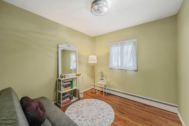 living area featuring hardwood / wood-style flooring and a baseboard heating unit