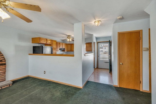 kitchen featuring ceiling fan, black fridge, dark carpet, and kitchen peninsula