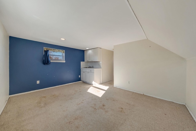 interior space with sink, vaulted ceiling, and light carpet