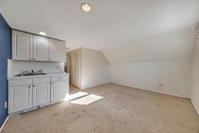 bonus room with lofted ceiling, sink, and light carpet