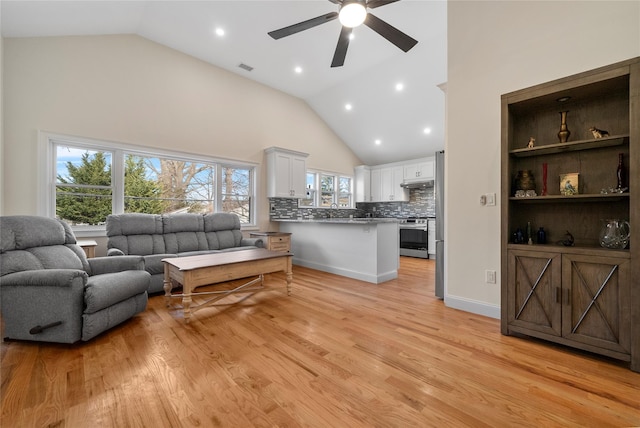 living room with high vaulted ceiling, ceiling fan, and light wood-type flooring