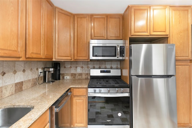 kitchen with stainless steel appliances, backsplash, and light stone counters