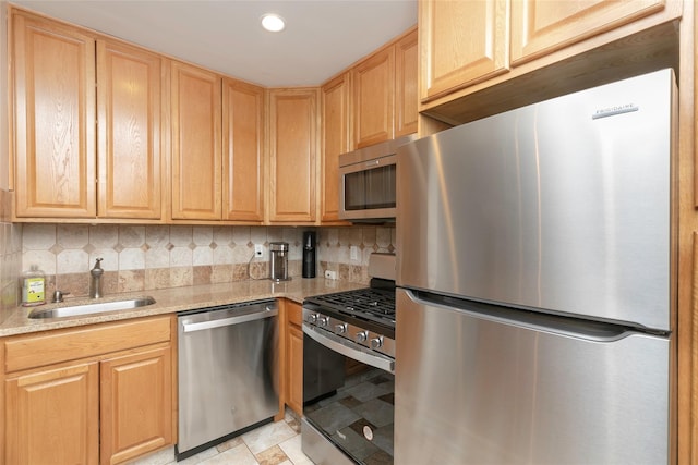 kitchen with appliances with stainless steel finishes, sink, light brown cabinetry, and decorative backsplash