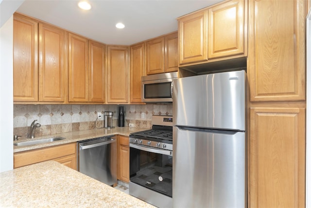 kitchen with appliances with stainless steel finishes, sink, light stone counters, and backsplash