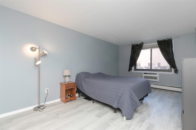 bedroom with an AC wall unit, light hardwood / wood-style floors, and baseboard heating