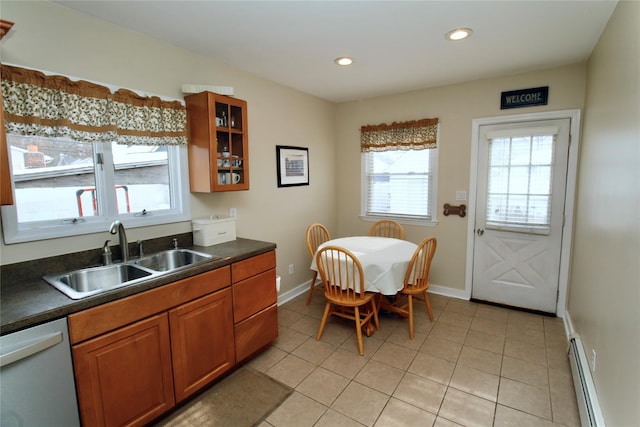 kitchen featuring a baseboard heating unit, dark countertops, a sink, and stainless steel dishwasher