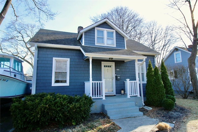 bungalow-style house with roof with shingles and a chimney