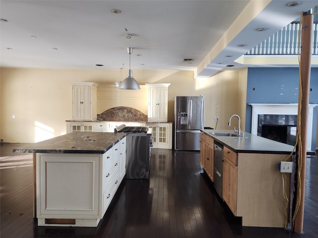 kitchen featuring sink, dark wood-type flooring, a kitchen island with sink, hanging light fixtures, and stainless steel appliances