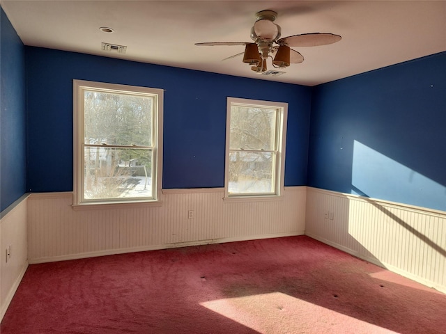 unfurnished room with plenty of natural light, carpet floors, and ceiling fan