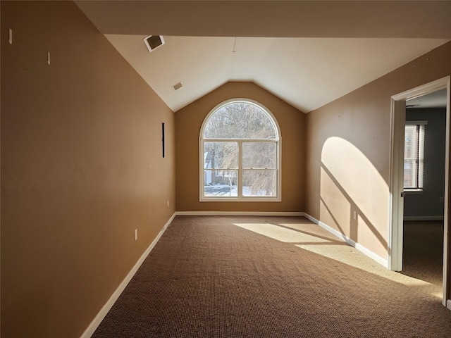 carpeted spare room featuring vaulted ceiling and plenty of natural light