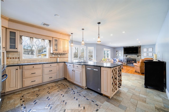 kitchen featuring hanging light fixtures, a stone fireplace, stainless steel dishwasher, and decorative backsplash