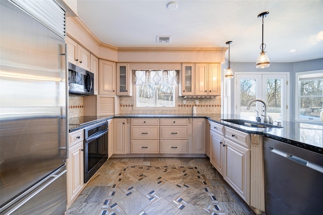 kitchen featuring pendant lighting, sink, backsplash, stainless steel appliances, and dark stone counters