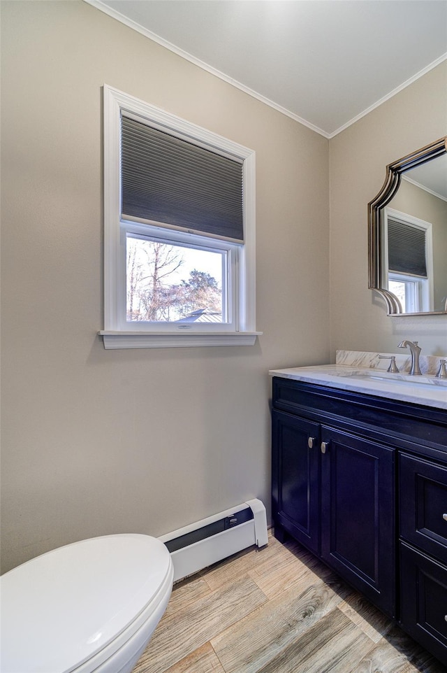 bathroom featuring vanity, wood-type flooring, ornamental molding, a baseboard radiator, and toilet