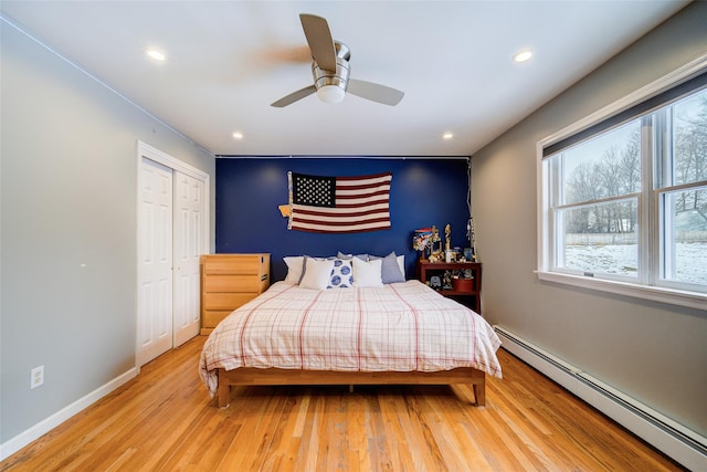 bedroom with multiple windows, baseboard heating, and light hardwood / wood-style floors