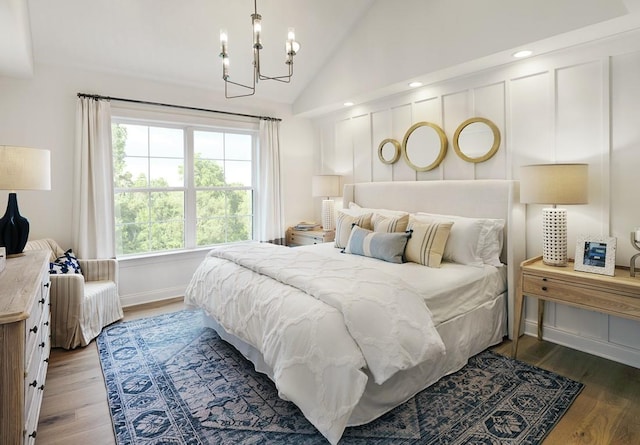 bedroom featuring wood-type flooring, lofted ceiling, and an inviting chandelier