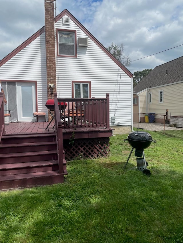 back of property with a wooden deck, a wall mounted air conditioner, and a yard