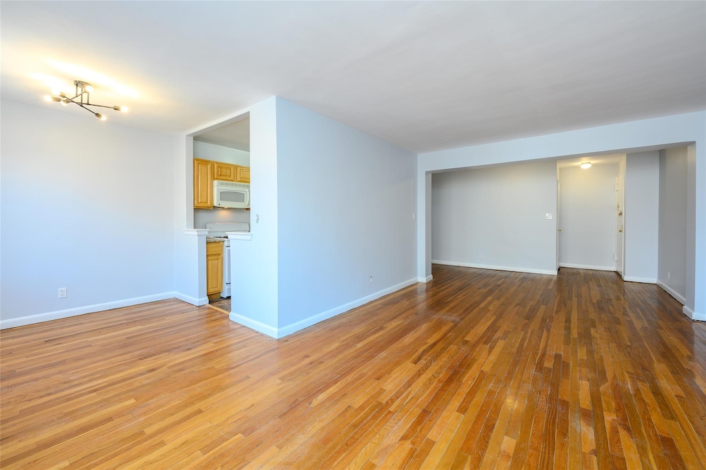 unfurnished living room featuring a notable chandelier and light hardwood / wood-style flooring