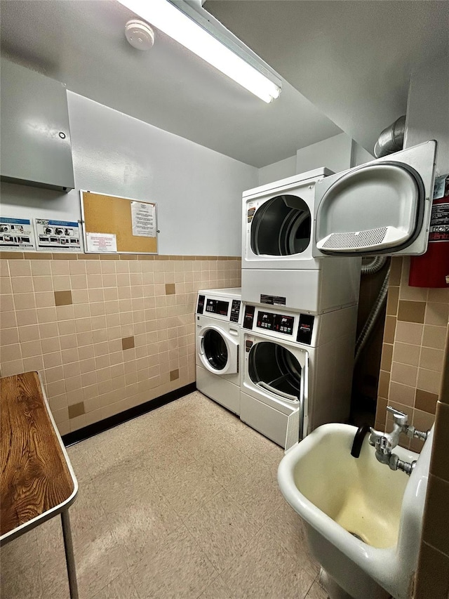 washroom featuring stacked washer and dryer, sink, tile walls, and washing machine and dryer