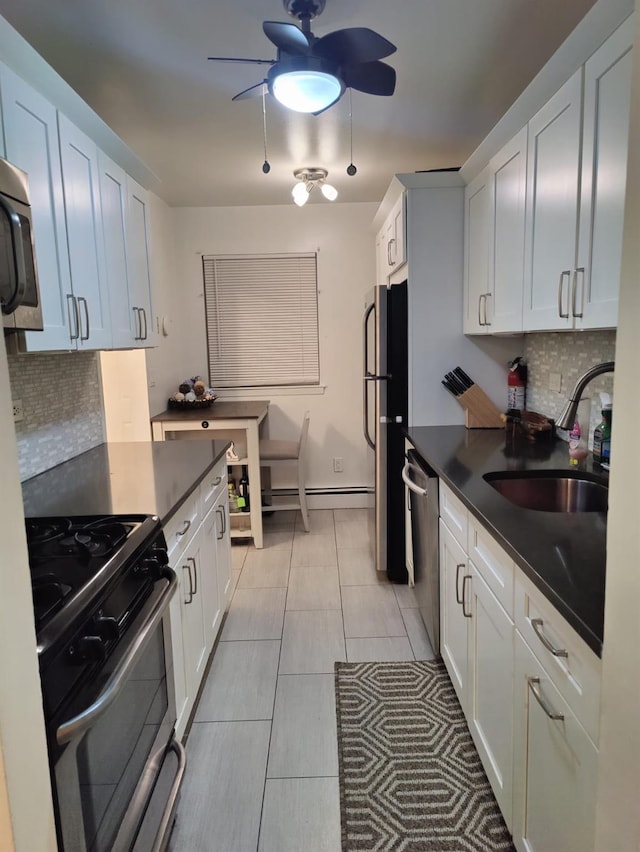 kitchen with sink, light tile patterned floors, appliances with stainless steel finishes, white cabinets, and decorative backsplash