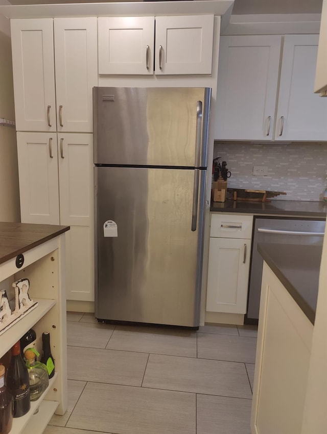 kitchen featuring tasteful backsplash, light tile patterned floors, stainless steel appliances, and white cabinets