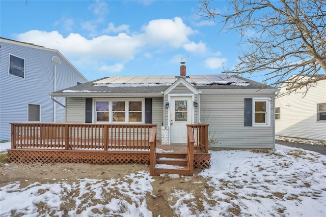 snow covered back of property with a deck