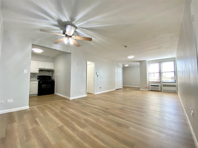 unfurnished living room with ceiling fan, radiator, light hardwood / wood-style floors, and a wall unit AC