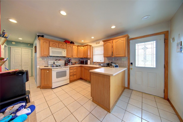 kitchen with tasteful backsplash, white appliances, kitchen peninsula, and a wealth of natural light