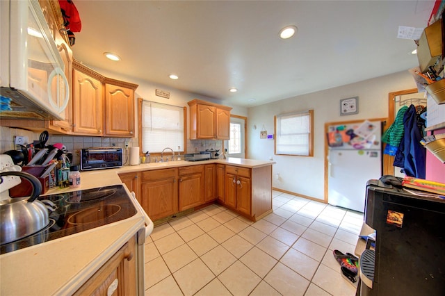 kitchen with light tile patterned flooring, sink, kitchen peninsula, white appliances, and backsplash