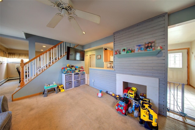 recreation room with light colored carpet, a fireplace, and ceiling fan