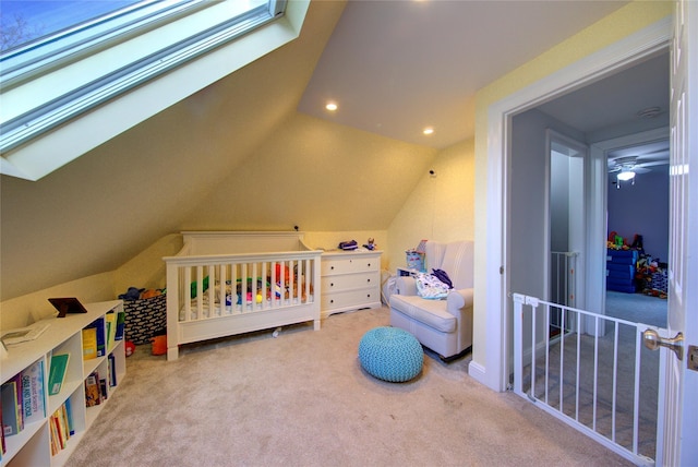 carpeted bedroom featuring a crib and lofted ceiling with skylight