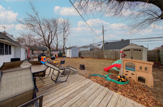 wooden deck featuring a playground and a storage unit