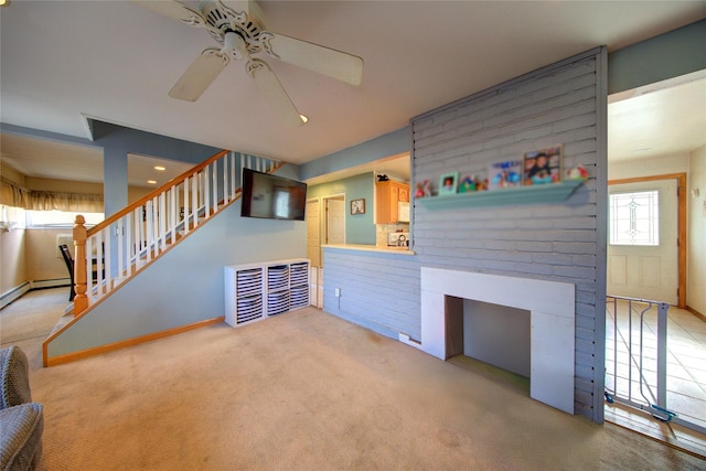 unfurnished living room with baseboards, carpet, stairway, and a ceiling fan